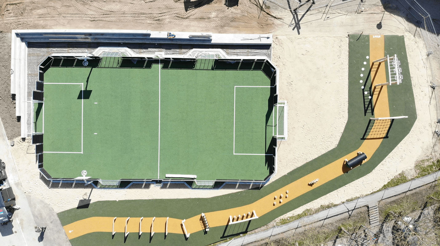 Udendørs bevægelsesmiljø med en multibane og en forhindringsbane med gummibelagt underlag.