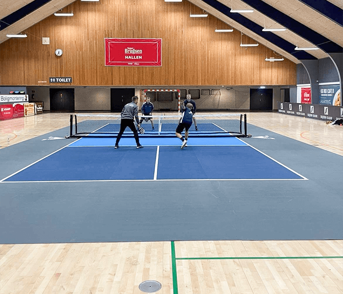 Fire pickleballspillere spiller pickleball på en True Court indendørs pickleballbane i Ringkøbing Skjern Kulturcenter.