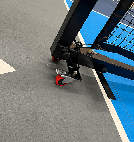 Et pickleball-konkurrencenet med transporthjul på True Court-gulv på en indendørs pickleballbane.