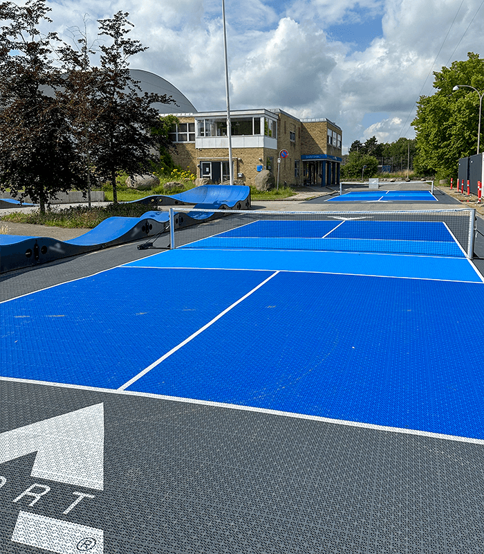 To udendørs pickleballbaner med vedligeholdelsesfrie, skridsikre PP-fliser fra A-Sport og en pumptrack bane.