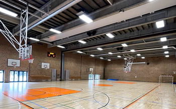 Loftmonterede motorbasketstativer og gulvopstregning af basketballbane i hallen.