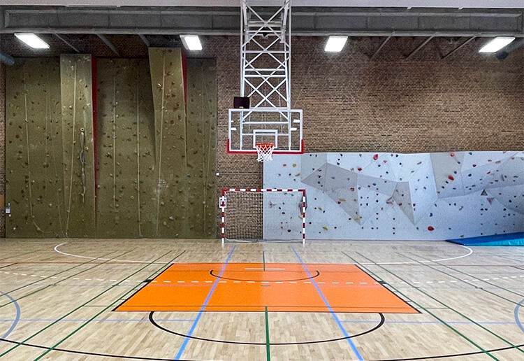 Loftmonterede motorbasketstativer og gulvopstregning af basketballbane i hallen.