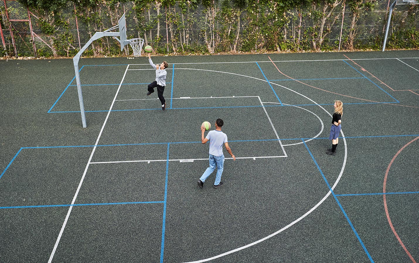 3 der spiller basketball på gummibelægning