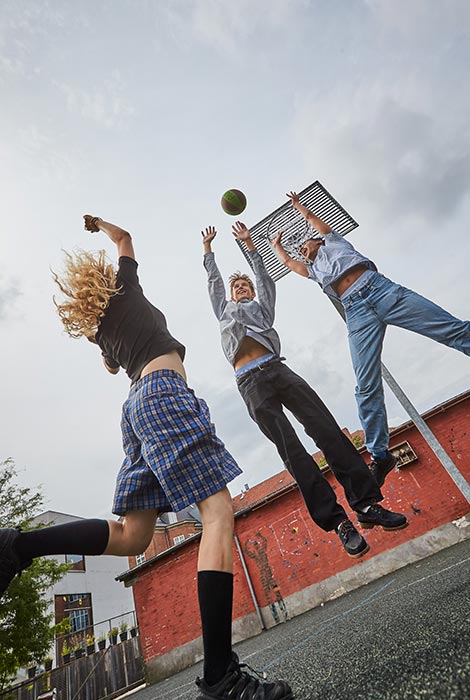3 personer spiller basket på basketballbane