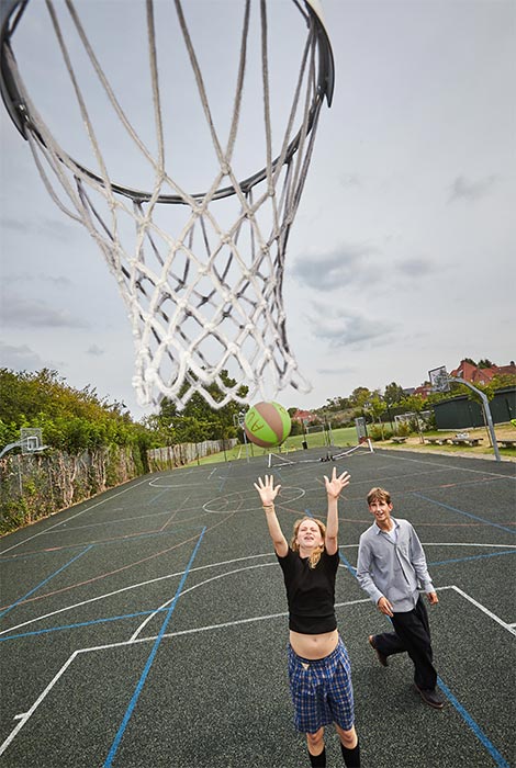 2 personer spiller basketball på baskeball bane