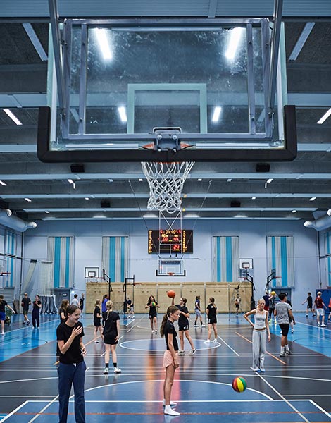 Elever der spiller basketball i den store hal
