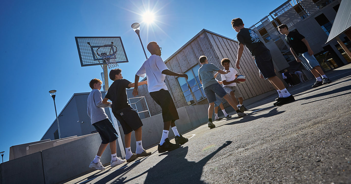 Drenge spiller basketball på bane